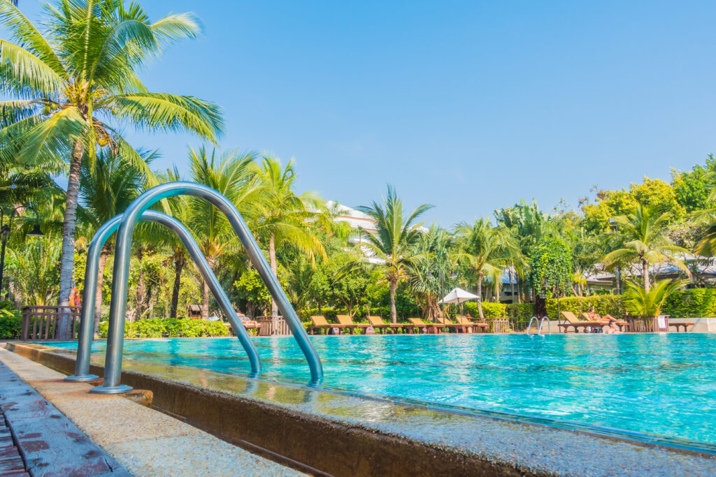 Beautiful luxury swimming pool with palm tree and sea background in hotel pool resort - Boost up color Processing