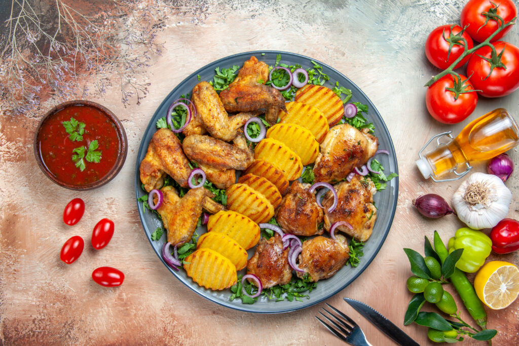 top-close-up-view-chicken-chicken-wings-potatoes-onion-herbs-vegetables-sauce-fork-knife